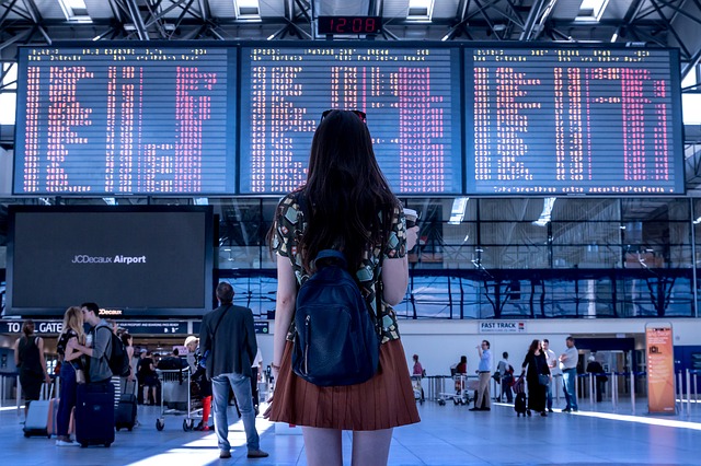 Girl in airport, looking at international travel destination arrivals & departures