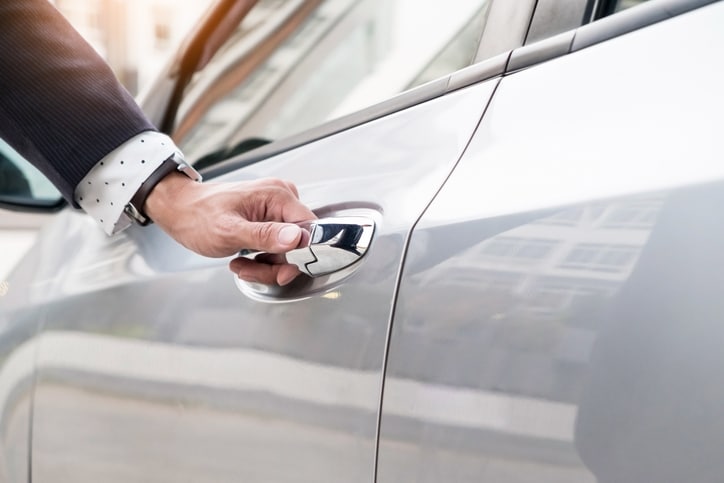 Chauffeur's hand on handle. Close-up of man in formal wear opening a passenger car door