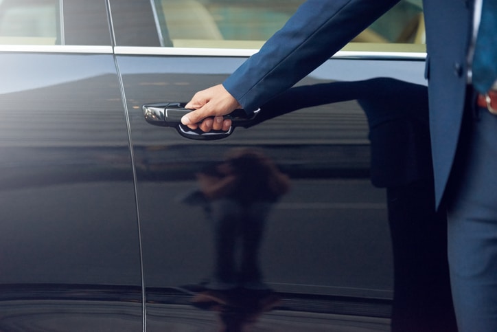 Private car service for business travellers - chauffeur opening car door