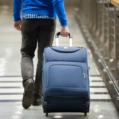 Man pulling suitcase through airport